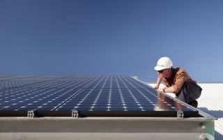 A solar tech is surveying a solar array on a rooftop.